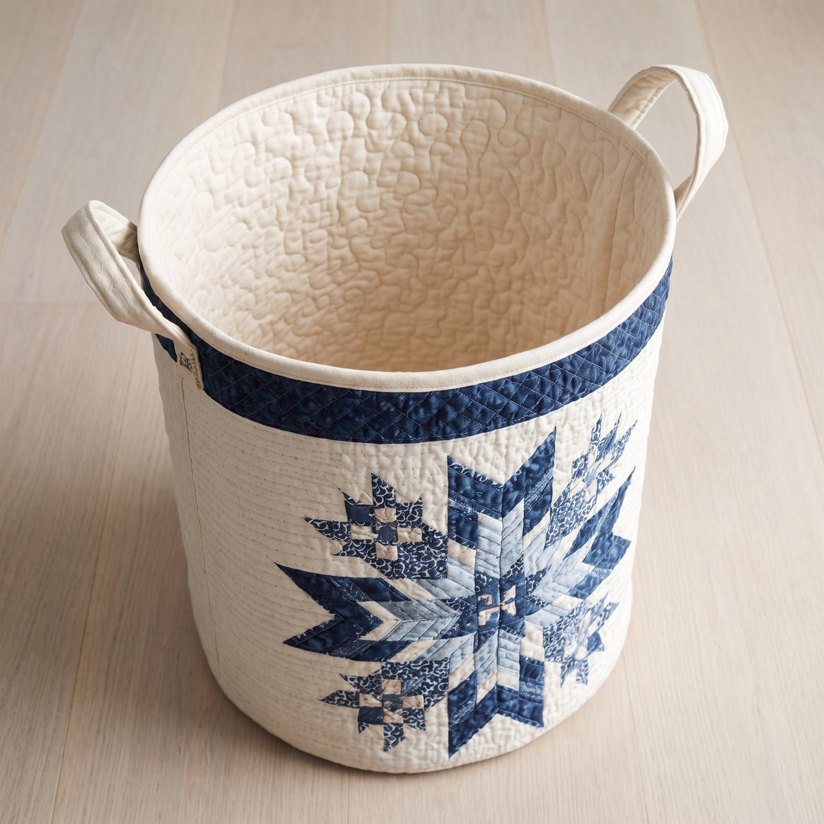 Lorena hand-quilted laundry basket with a navy quilt star snowflake medallion, open empty view