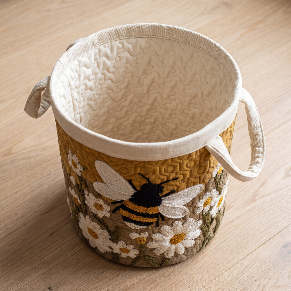 Luigia hand-quilted laundry basket with a bumblebee among white daisies, open empty view