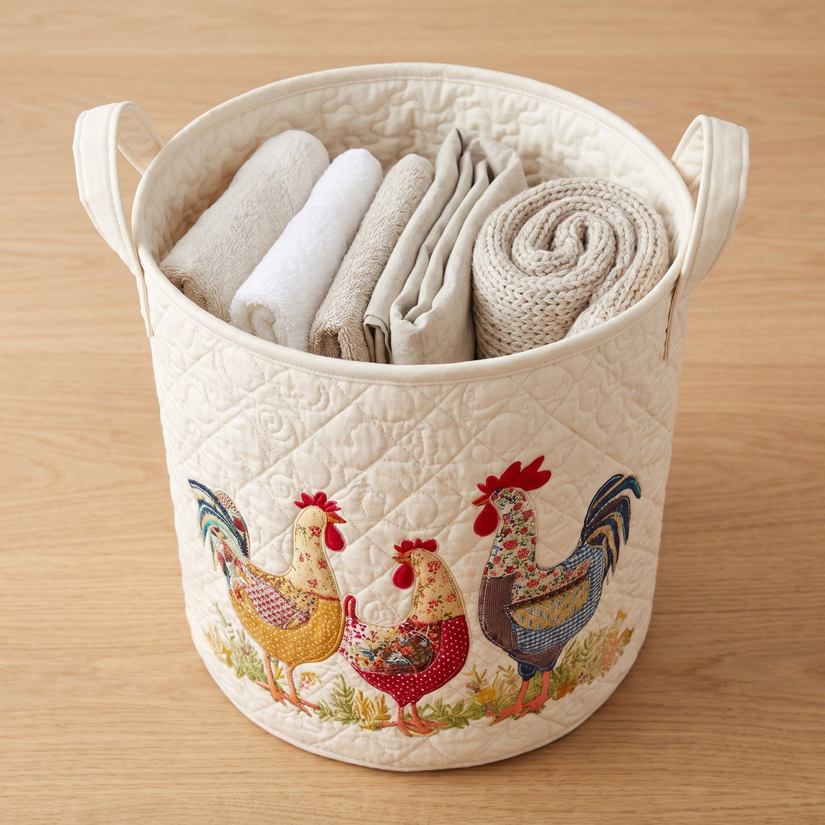 Manuela hand-quilted laundry basket with three patchwork hens, filled with folded towels