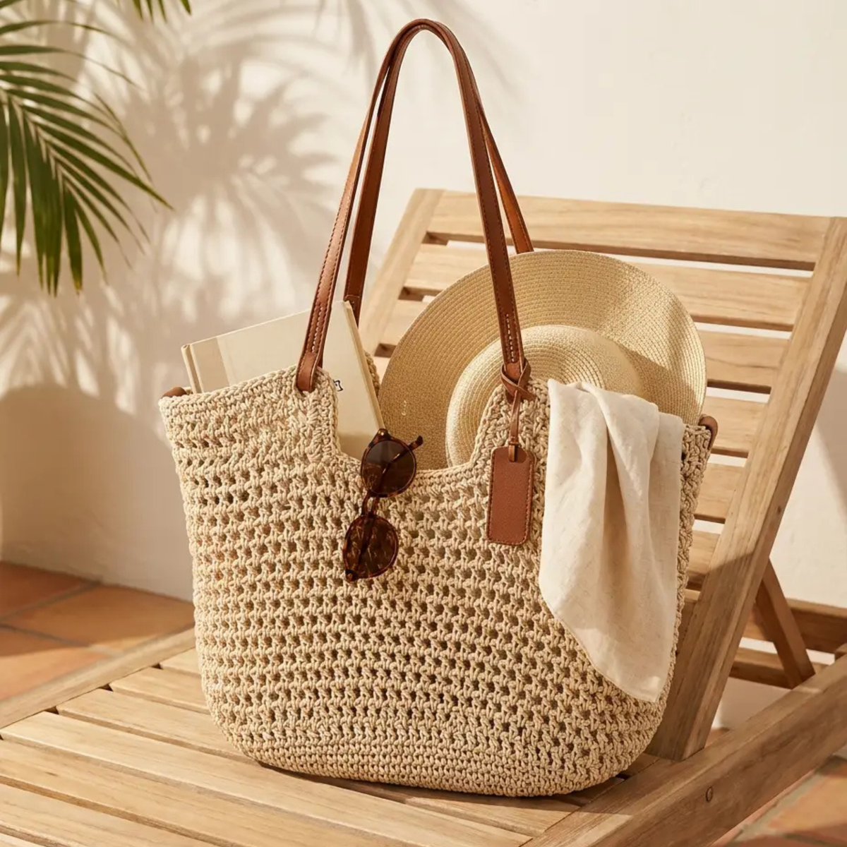 Clare handwoven crochet tote bag in khaki with brown straps, packed with a hat and book