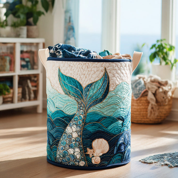 Rina hand-quilted laundry basket with a teal mermaid tail rising from the waves, front view by a window