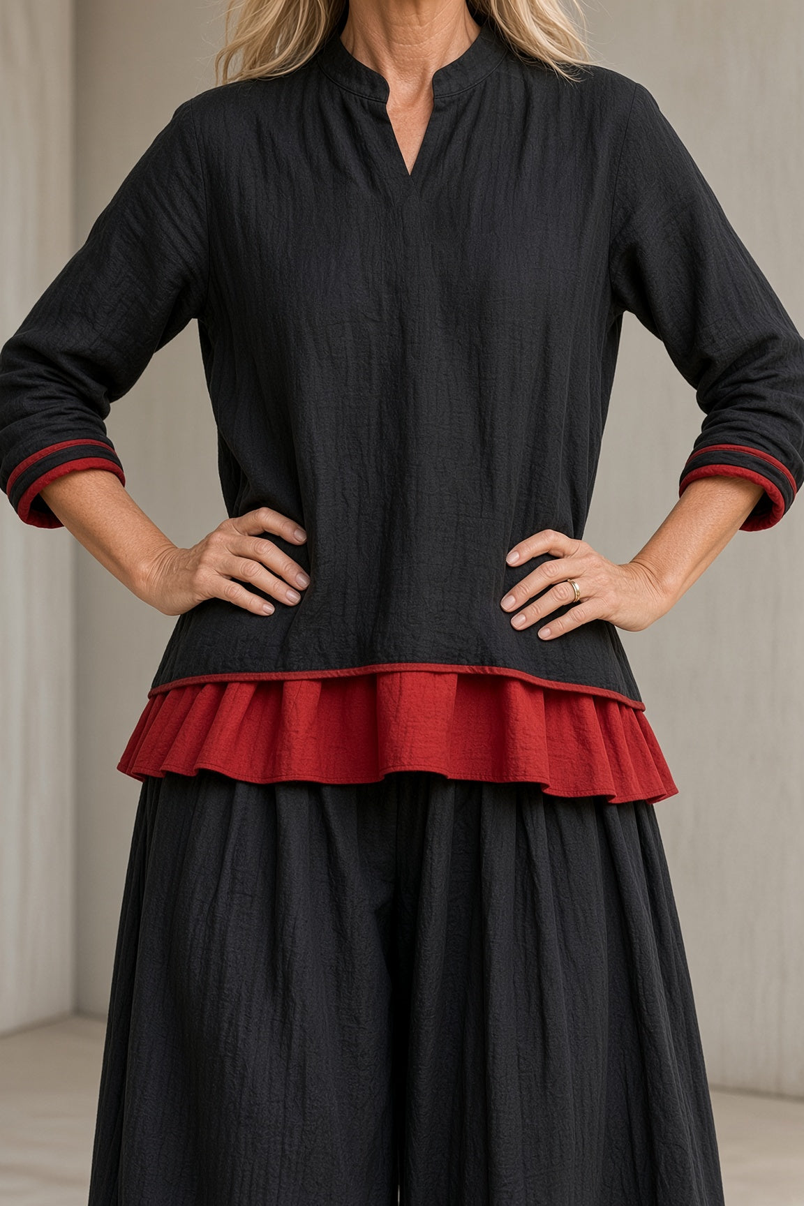 Marietta layered tunic and balloon trouser set in black, close-up of red layered hem